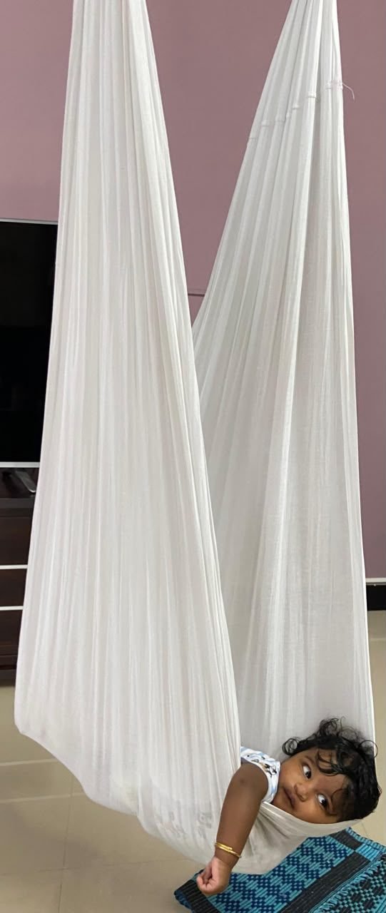 Baby Dhuruvan peeking out of a white cloth swing